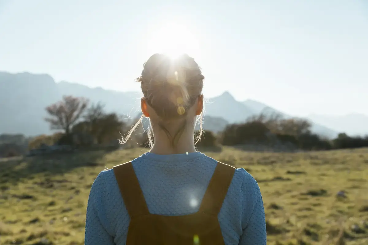 Mujer de espaldas mirando hacia las montañas al amanecer
